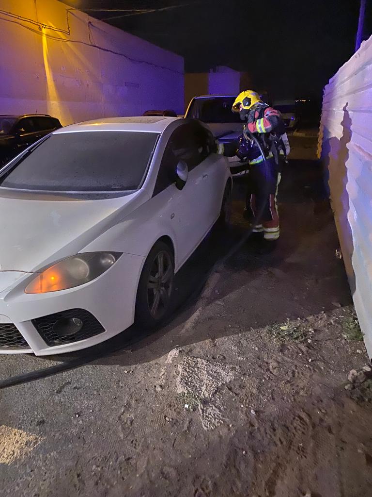 Un bombero inspeccionando el vehículo incendiado.