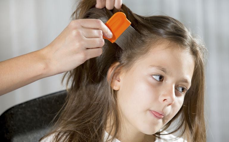 Una niña espera paciente mientras le pasan la lendrera. 