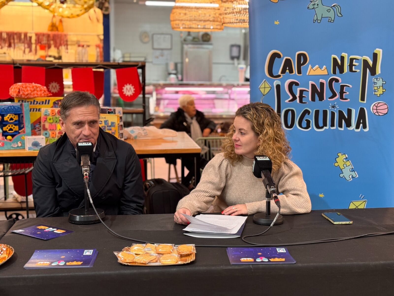 El regidor de Promoció Econòmica de Reus, Josep Baiges i la periodista de SER Tarragona - Ràdio Reus, Eva Hidalgo, durant el programa especial Cap Nen Sense Joguina al Mercat de Reus