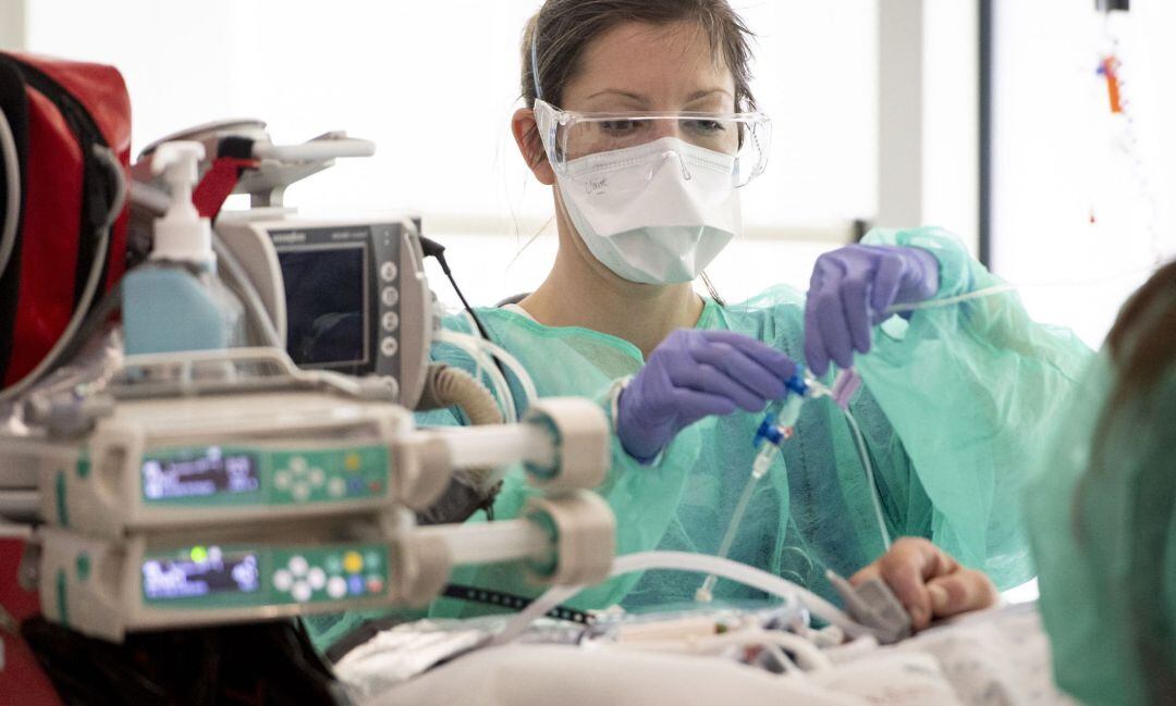 Una sanitaria atiende a un enfermo de coronavirus.