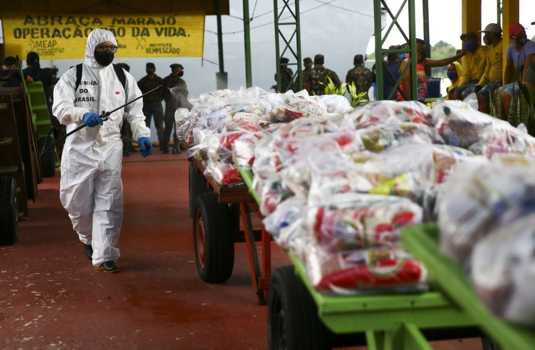 Un soldado brasileño desinfecta las bolsas de ayuda humanitaria que llegaron al municipio paraense de Afua, en el norte de Brasil, para paliar los estragos de la pandemia de la COVID-19.