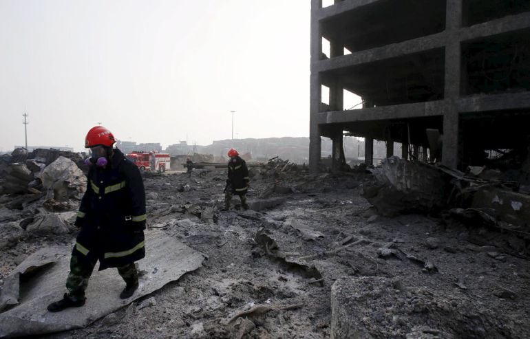 Un bombero porta máscaras de gas mientras camina cerca de un edificio derrumbado. 