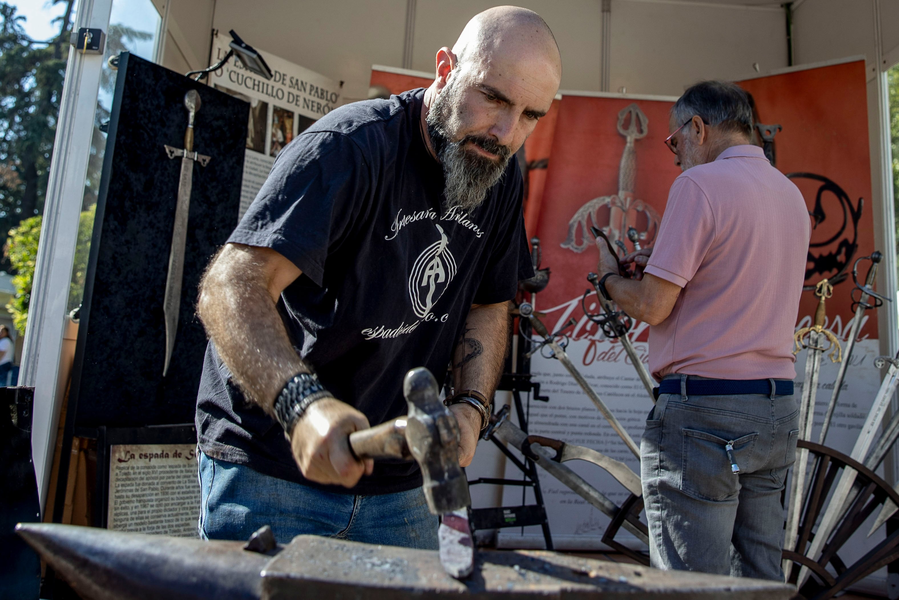 Un artesano forjador trabaja en su puesto de la feria de artesanía Farcama 2023, uno de los atractivos turísticos de Toledo en este Puente del Pilar
