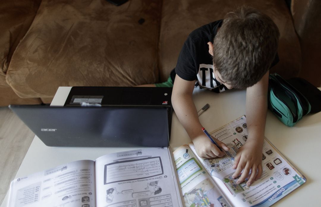 Un alumno de primaria de Madrid hace los deberes de la asignatura de Inglés con varios libros y un ordenador a menos de un mes de terminar en casa el curso escolar 2019-2020 por la pandemia del Covid-19.