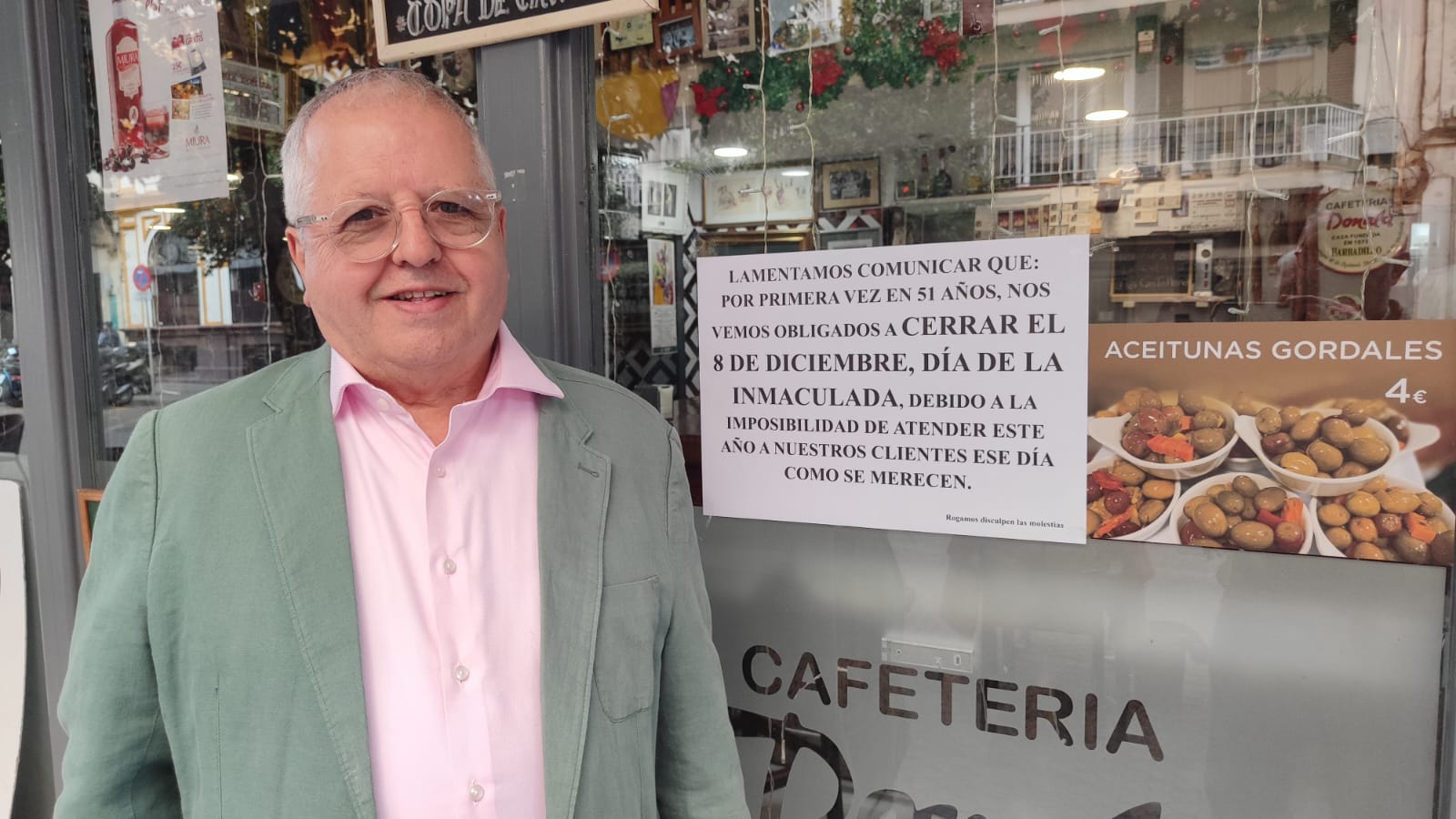 Mariano García Romero posa ante el cartel que ha colocado en el escaparate de su Restaurante Donald