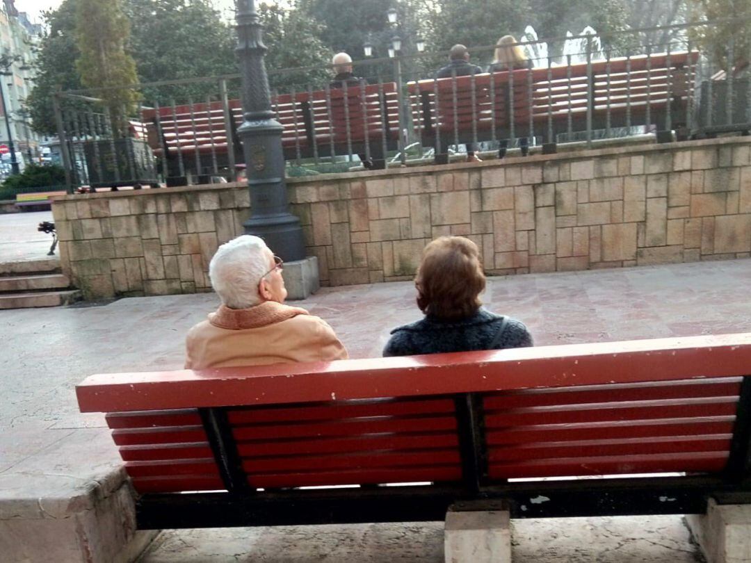 Ancianos descansando en un banco de la Plaza de La Escandalera de Oviedo