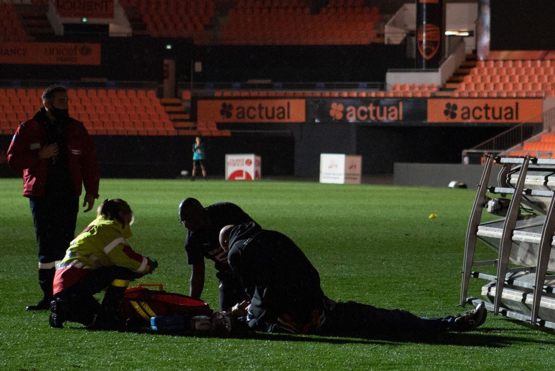 Los servicios médicos atienden al empleado en el césped del estadio.