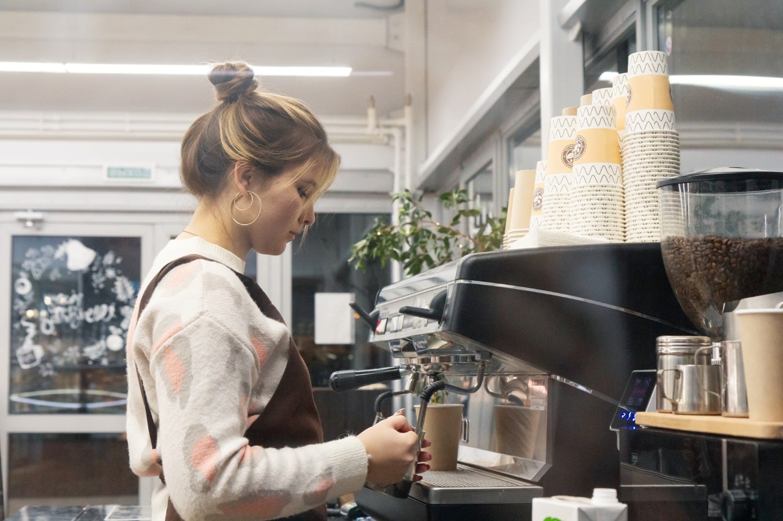 Una camarera prepara un café en un establecimiento de hostelería