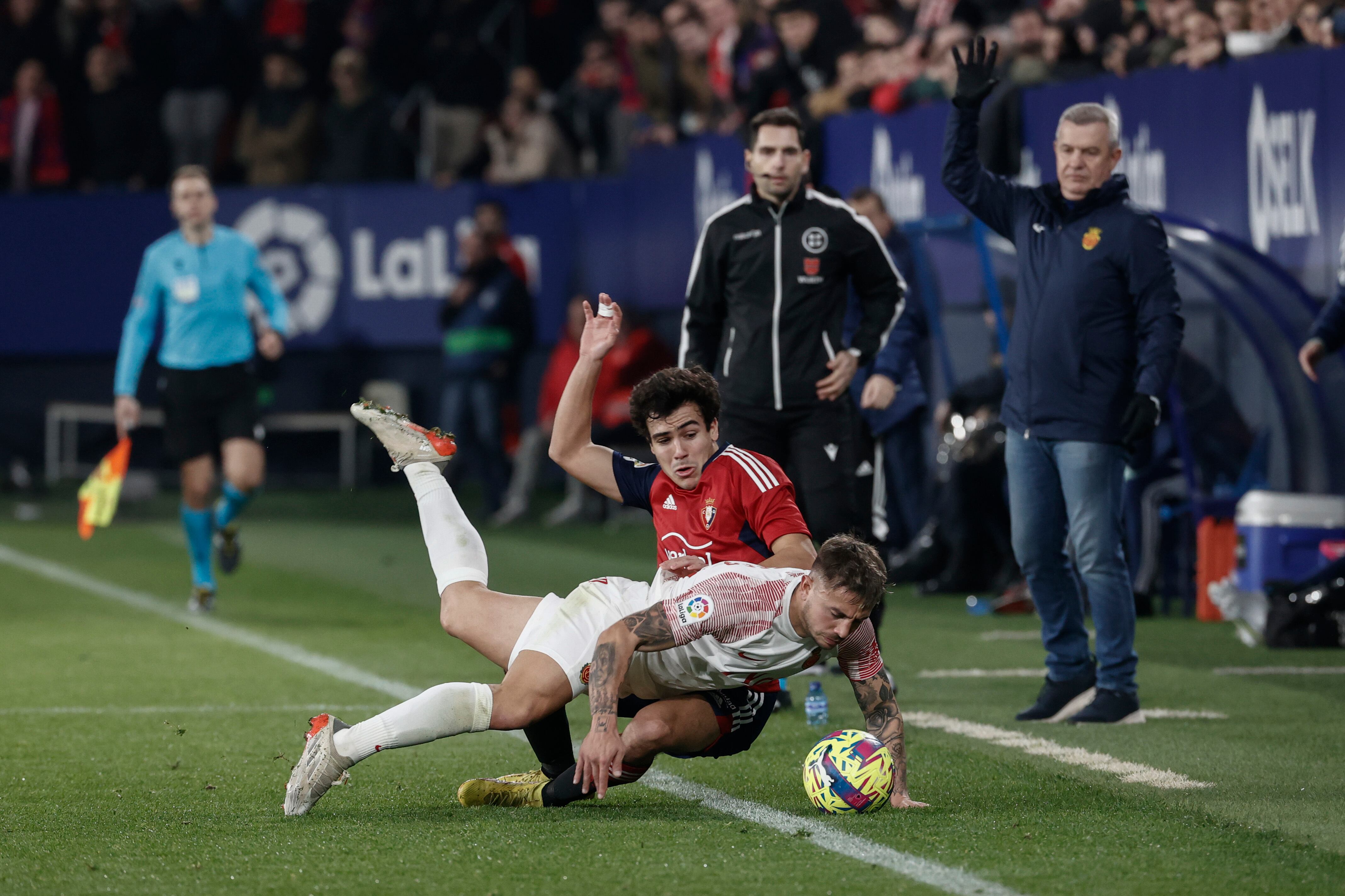 PAMPLONA (ESPAÑA), 14/01/2023.- El mediocentro del Mallorca, Dani Rodríguez (delante) cae en una acción con el defensa del Osasuna, Manu Sánchez (detrás), durante el partido que enfrenta al CA Osasuna y al RCD Mallorca, y que se disputa este sábado en el estadio El Sadar de Pamplona, (Navarra). EFE/ Jesus Diges
