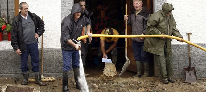 Vecinos del pueblo navarro de Ochagavia limpian el barro acumulado en las calles de la localidad tras el desbordamiento del río Salazar debido a las intensas lluvias que han caído en la zona.