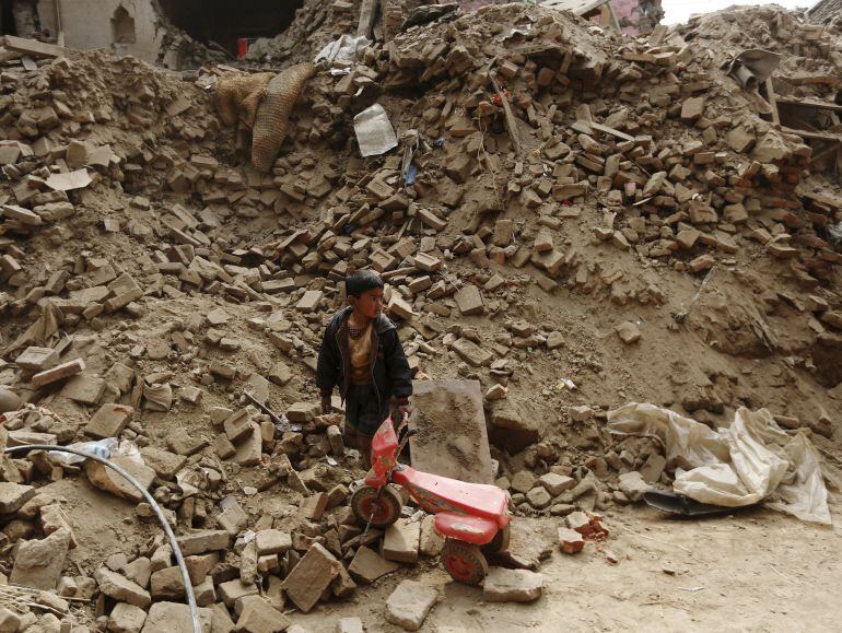 A boy carries his tricycle through his home destroyed by the April 25 earthquake in Bhaktapur, Nepal, May 6, 2015. REUTERS/Olivia Harris 