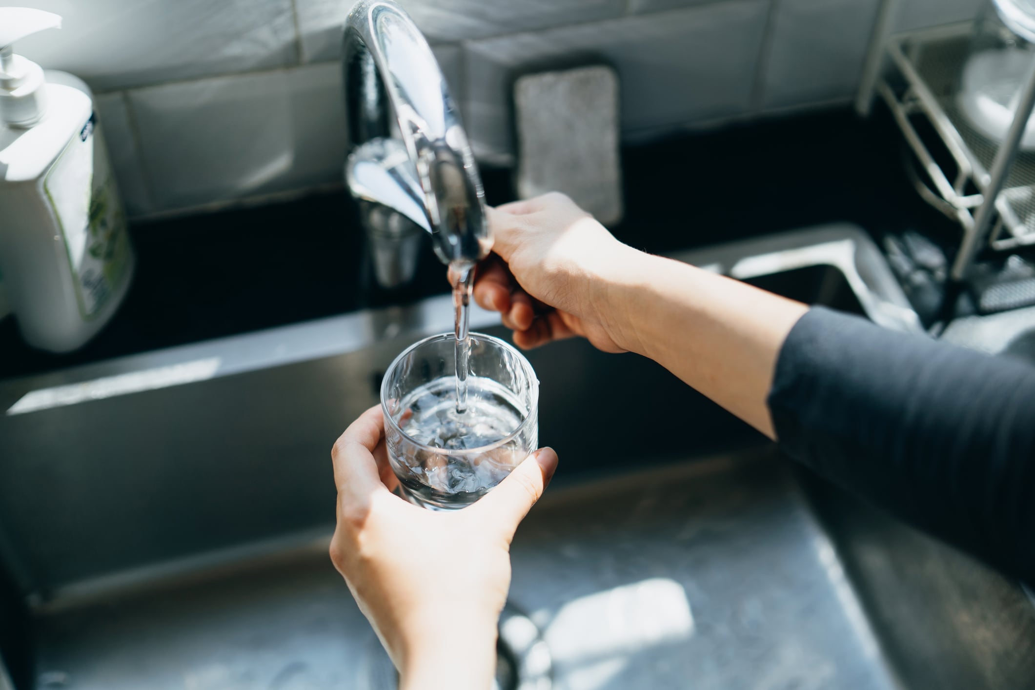 Una mujer se llena un vaso con agua de grifo