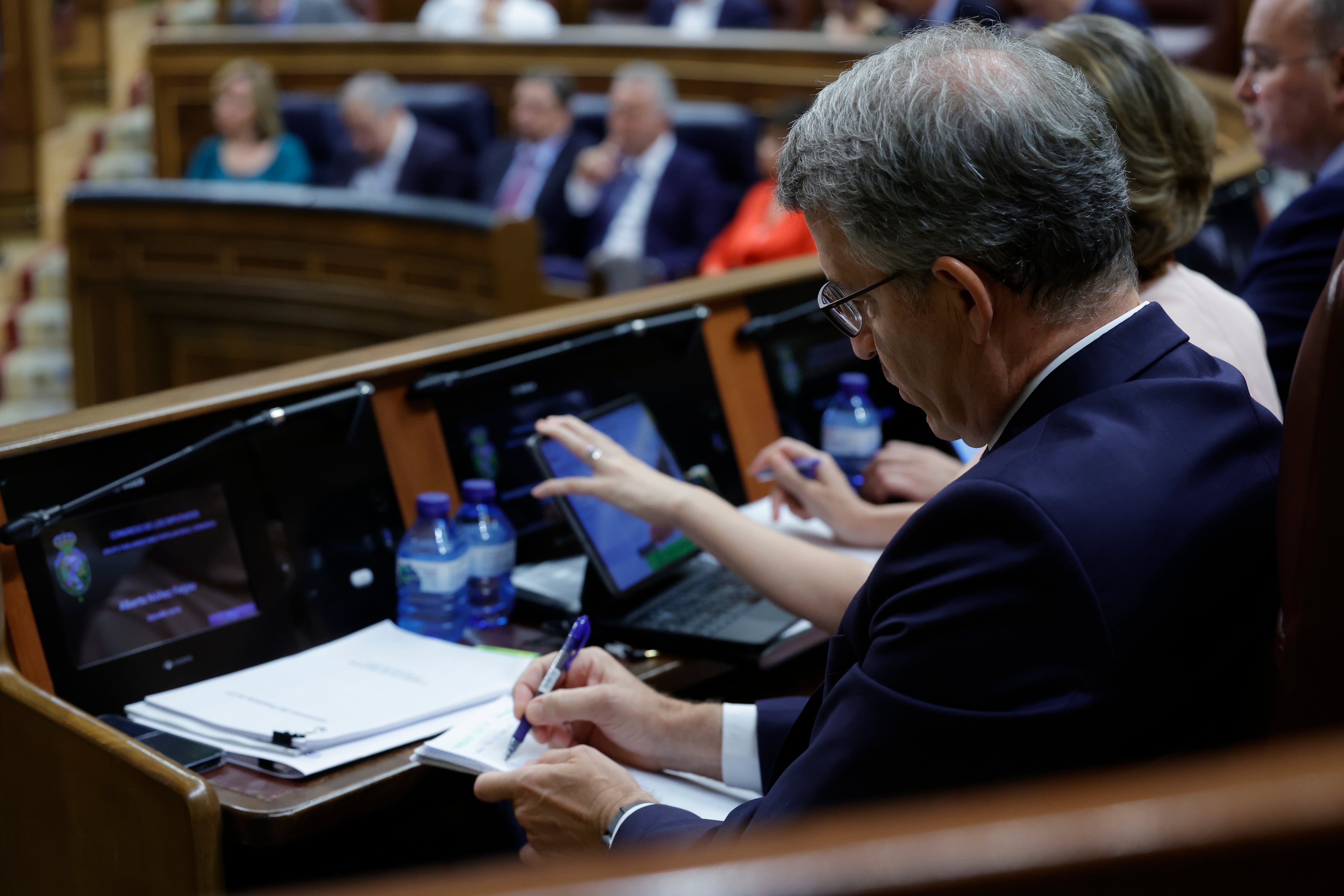 El líder del Partido Popular, Alberto Núñez Feijóo (d), mientras escucha la intervención del presidente del Gobierno, Pedro Sánchez en el Congreso