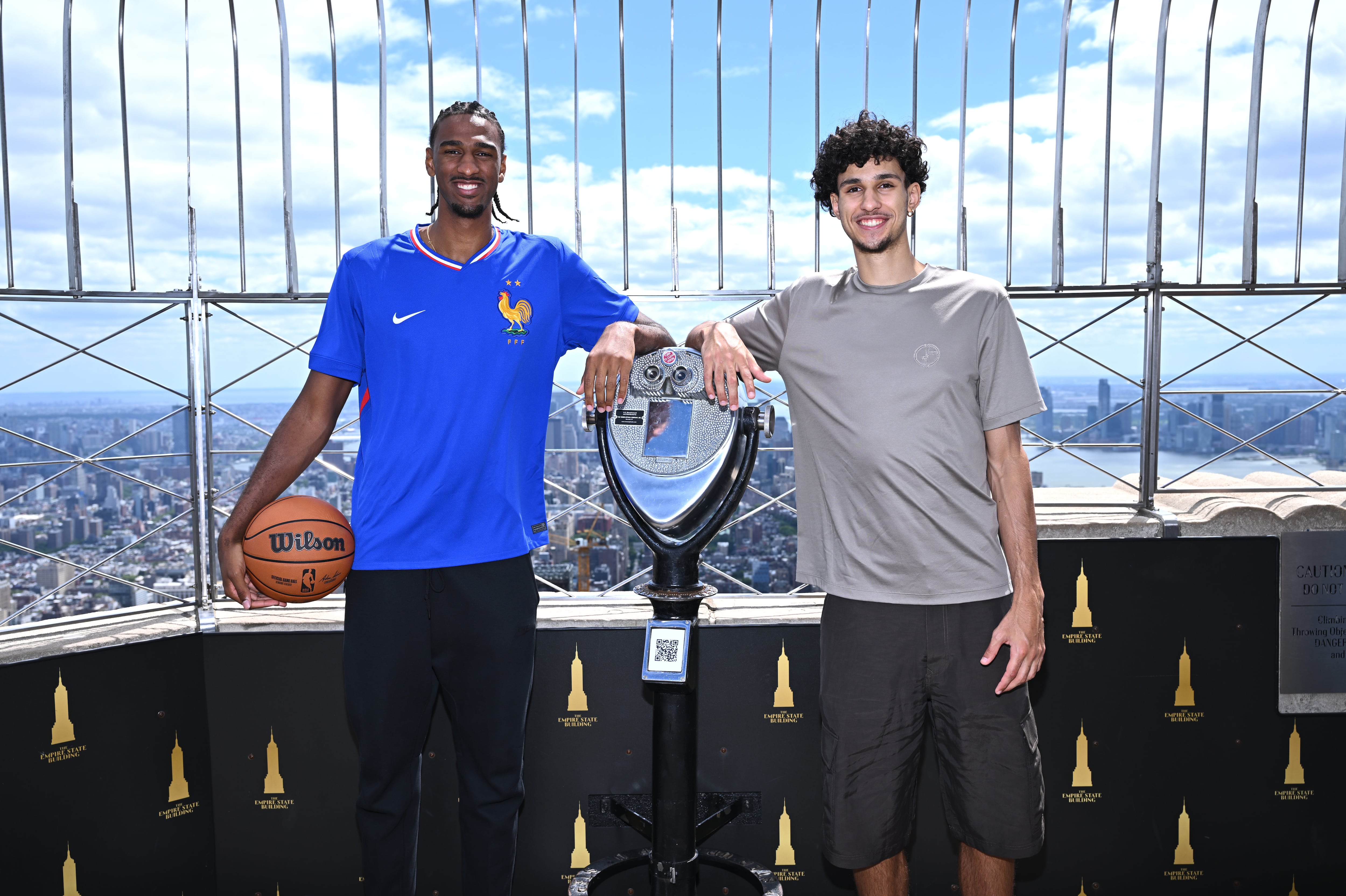 Alex Sarr (izquierda) y Zaccharie Risacher (derecha) posan en el Empire State Building tras la celebración del draft de la NBA