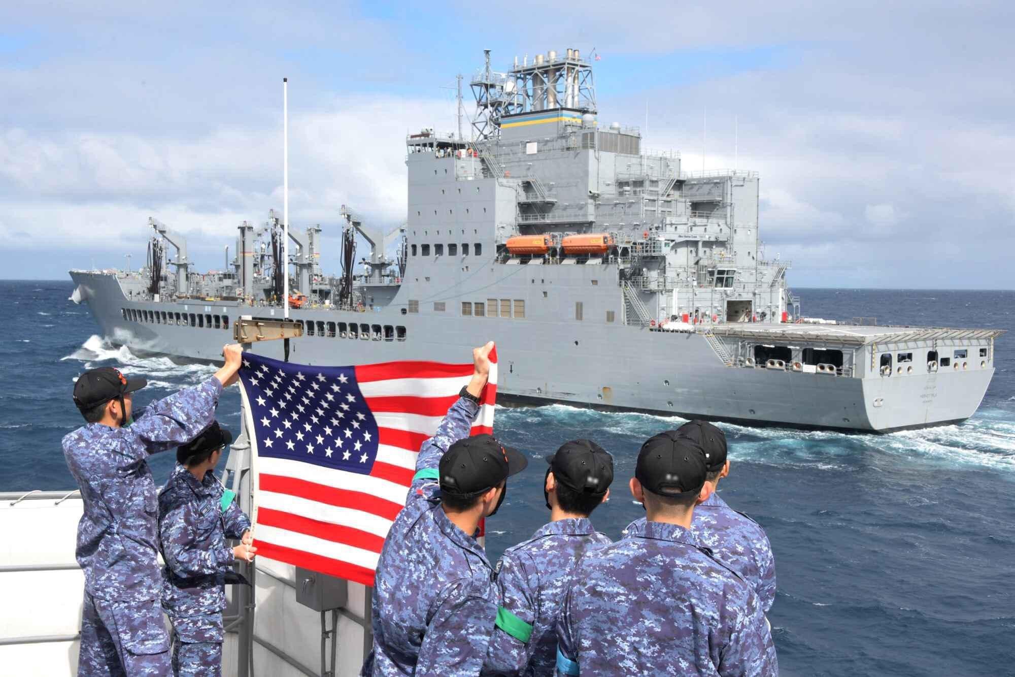 Soldados de EEUU muestran una bandera de su país hacia el USNS Harvey Milk en Norfolk el pasado año