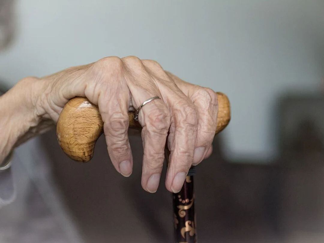 La mano de una anciana sujeta un bastón 