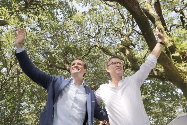 El presidente del Partido Popular, Pablo Casado (i), y el presidente de la Xunta de Galicia, Alberto Núñez Feijoo, saludan al comienzo del acto político celebrado hoy en la Carballeira de San Xusto, en la localidad coruñesa de Cotobade.