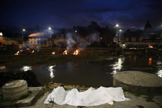 Un cura incinera los restos mortales de varias víctimas del seísmo de Nepal, en el centro de incineraciones de Pashupat, Katmandú.