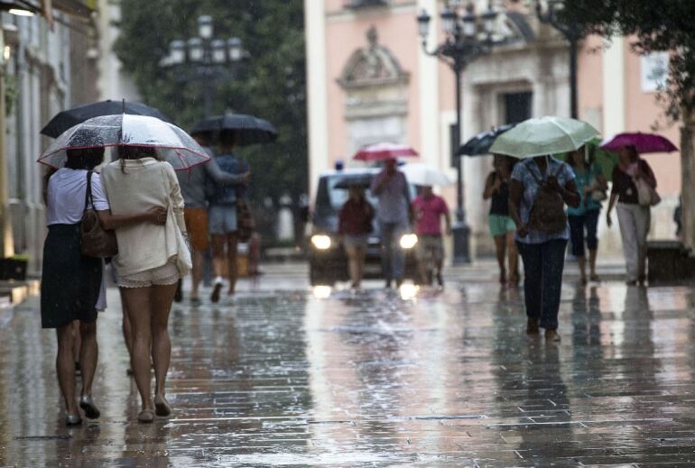 La Comunitat Valenciana está hoy en alerta amarilla, que se eleva a naranja en la zona sur de Valencia y norte de Alicante, ante la previsión de fuertes lluvias que pueden dejar hasta 30 litros por metro cuadrado en una hora. En la imagen los peatones se