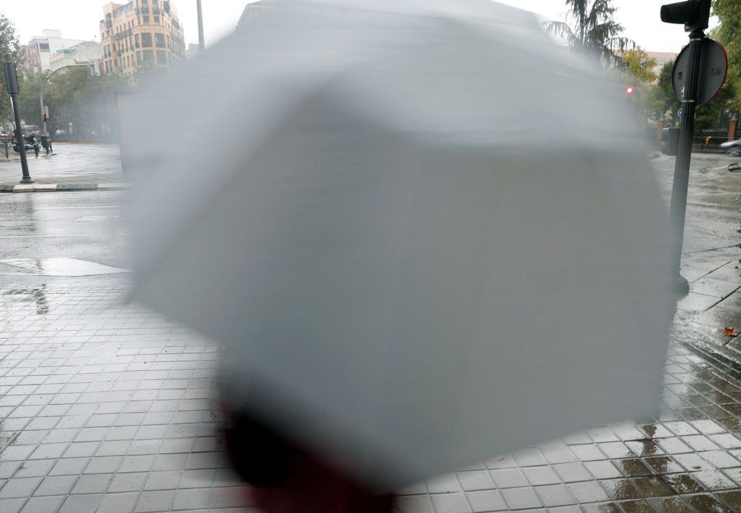 Una persona se cubre de la lluvia hoy en Madrid