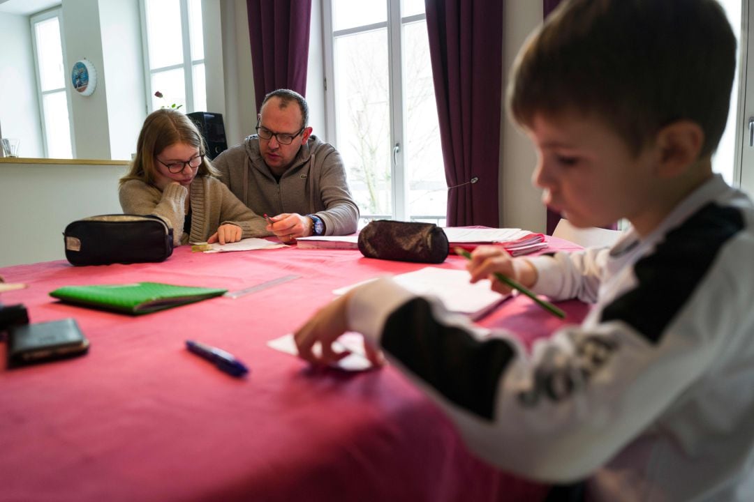 Un padre ayuda a sus hijos con los deberes durante el confinamiento por el coronavirus