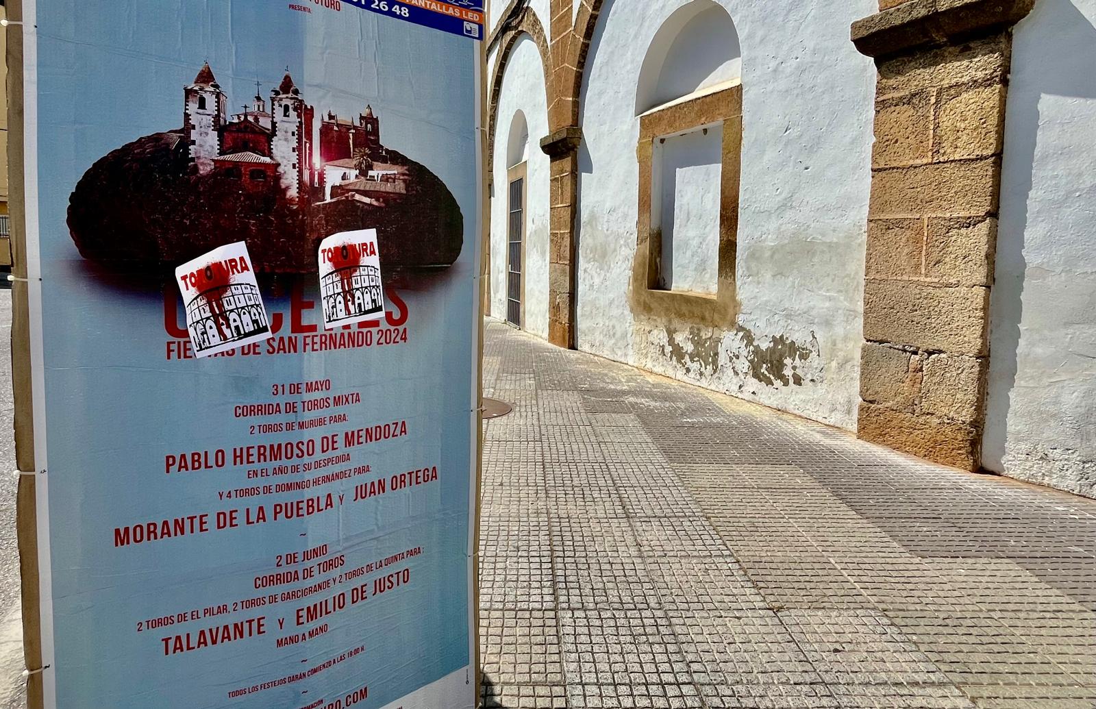 Cartel próximo a la plaza de toros de Cáceres con pegatinas que incluyen la palabra &quot;tortura&quot;.