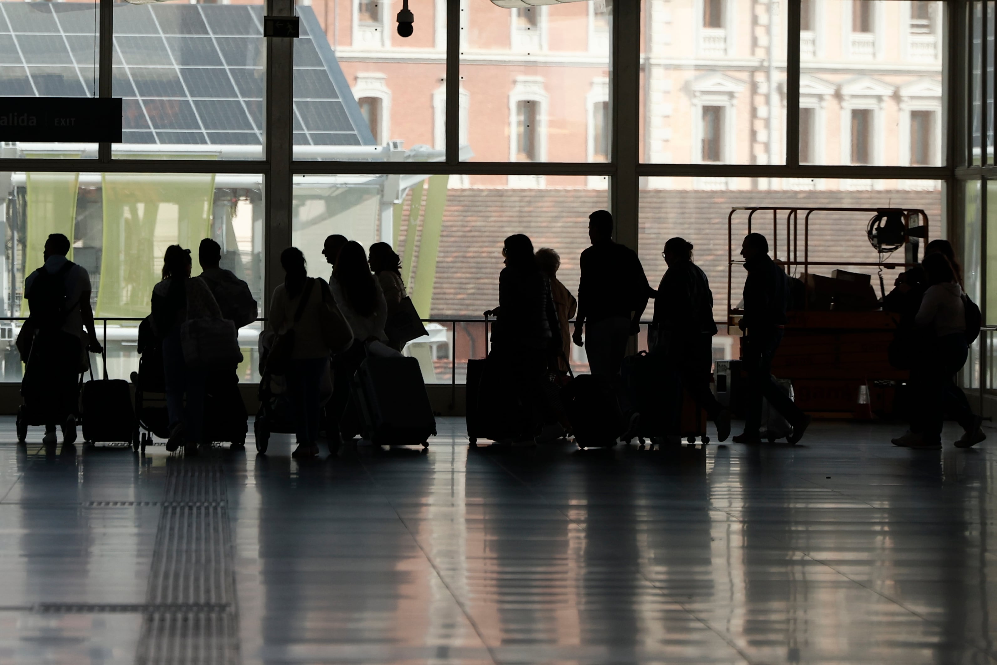 Varias personas esperan para montar en tren en la estación de Atocha en Madrid este domingo