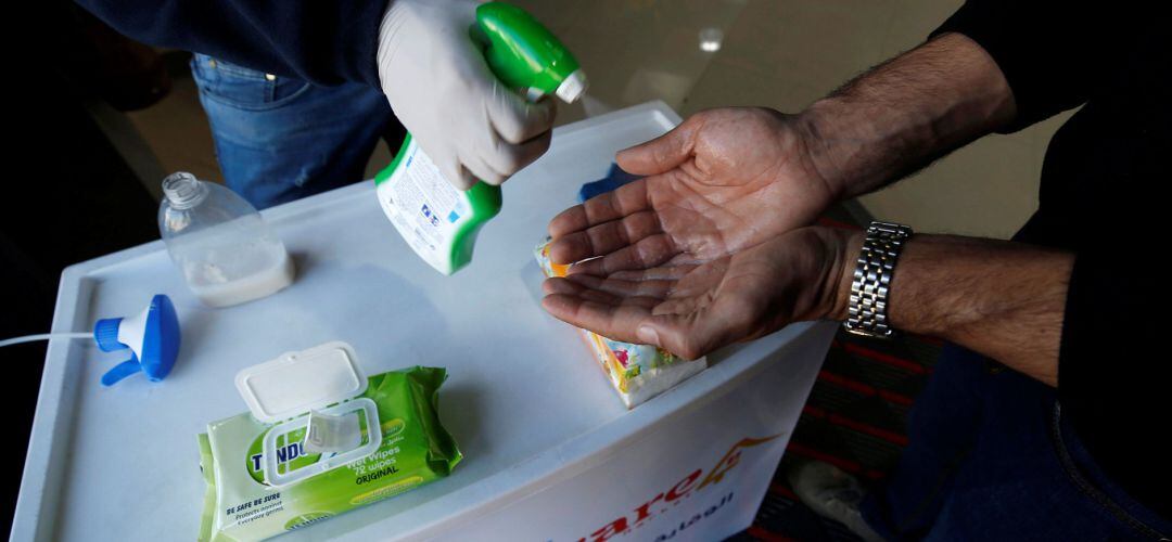 A Palestinian worker sanitizes the hands of a customer amid coronavirus precautions, in a supermarket in Gaza.