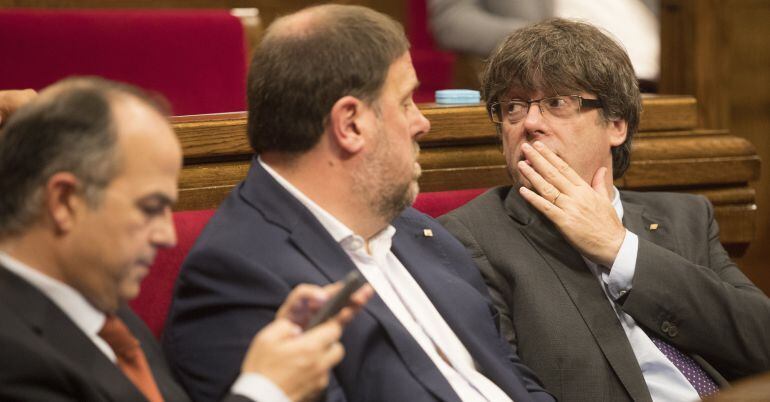 El presidente de la Generalitat, Carles Puigdemont (d), junto al vicepresidente Oriol Junqueras (c), y el conseller de la Presidencia y portavoz del gobierno catalán, Jordi Turull (i)