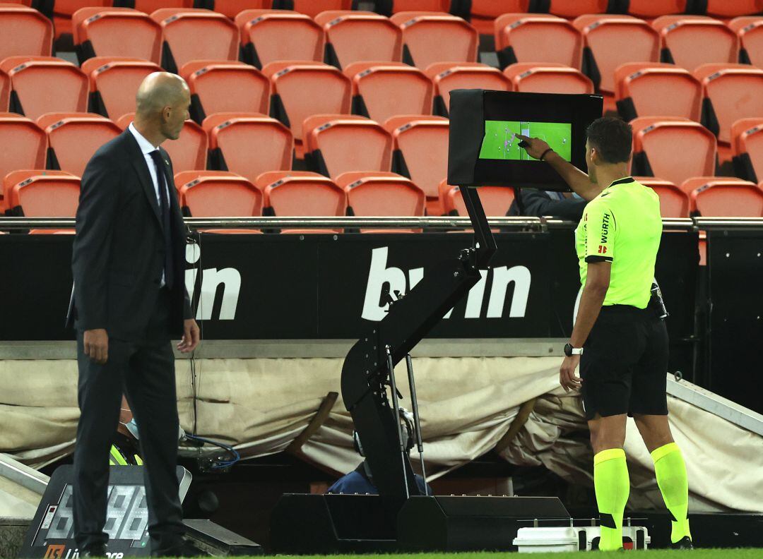 Gil Manzano mira el monitor ante la atenta presencia de Zidane en un partido de LaLiga