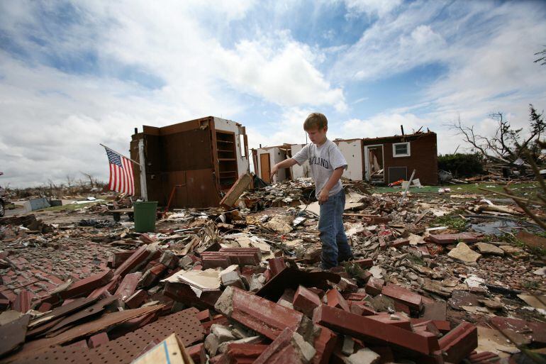 Un niño juega con un ladrillo entre los restos de su casa, en Greensburg (Kansas), destruida tras el paso de un tornado el 7 de mayo de 2007