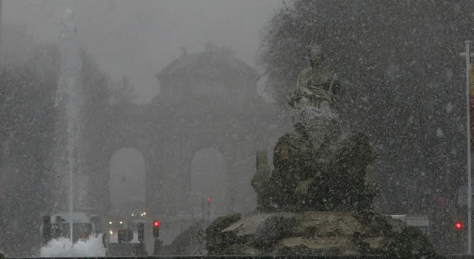 Vista de la madrileña fuente de Cibeles, con la puerta de Alcalá al fondo, bajo la nevada que ha caído este pasado miércoles sobre la capital