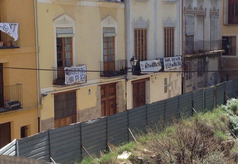 Los vecinos de la plaza han colocado carteles reclamado que les Corts que son las propietarias del solar vallado lo limpien. Albergan unas ruinas romanas del orígen de la ciudad descubiertas hace casi 20 años y que están rodeadas de maleza