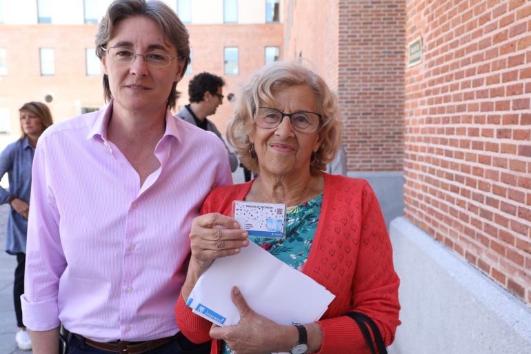 Marta Higueras y Manuela Carmena muestran la tarjeta de vecindad durante el acto al que han asistido este lunes en el patio de Conde Duque