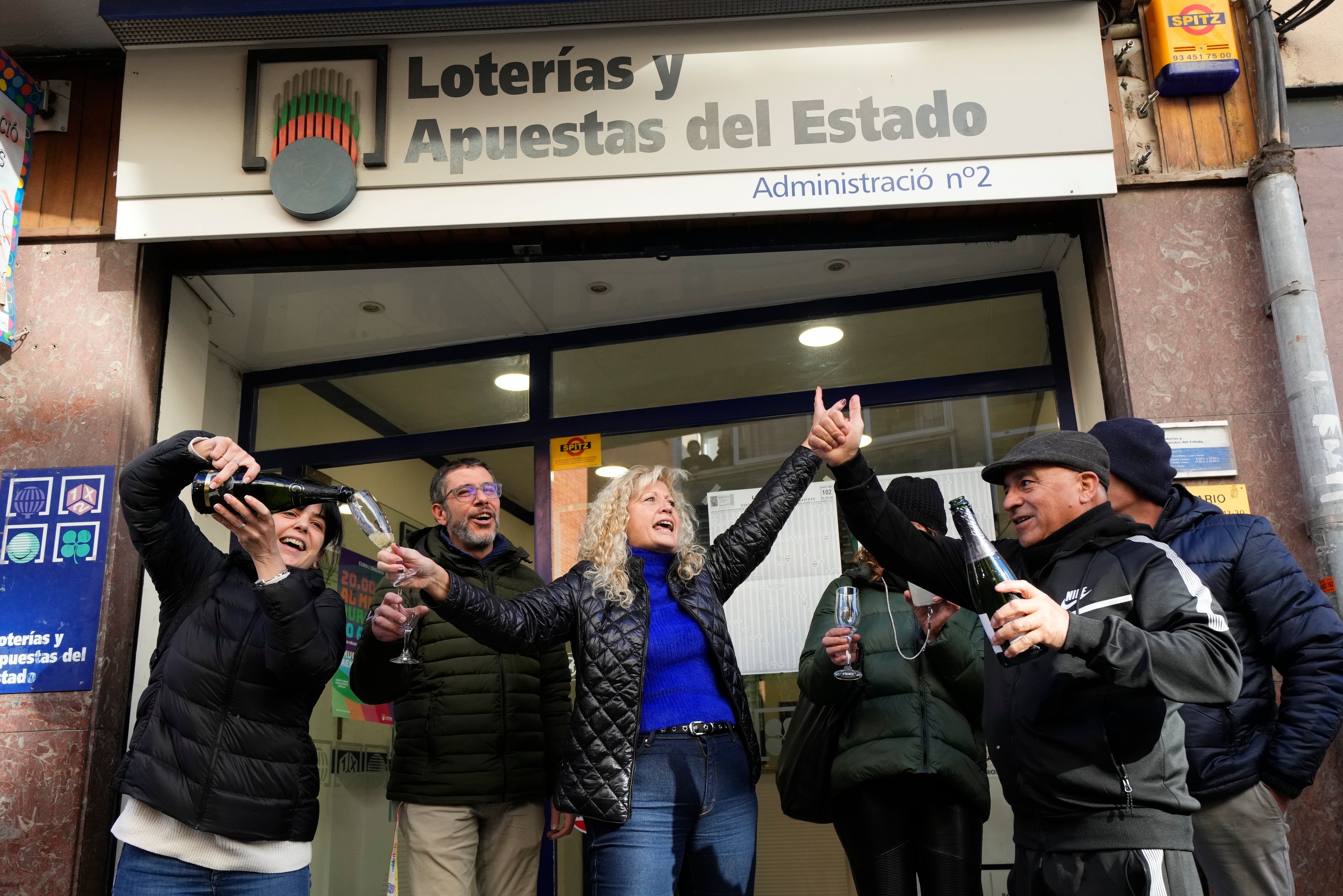 CORBERA DE LLOBREGAT (BARCELONA), 06/01/2024.- Los propietarios de la Administración nº2 de Corbera de Llobregat (Barcelona) celebran con algunos de los agraciados haber vendido décimos del primer premio del sorteo extraordinario de la lotería del Niño, celebrado este sábado y dotado con dos millones de euros por serie (200.000 euros al décimo), que ha recaído en el número 94.974. EFE/Alejandro García