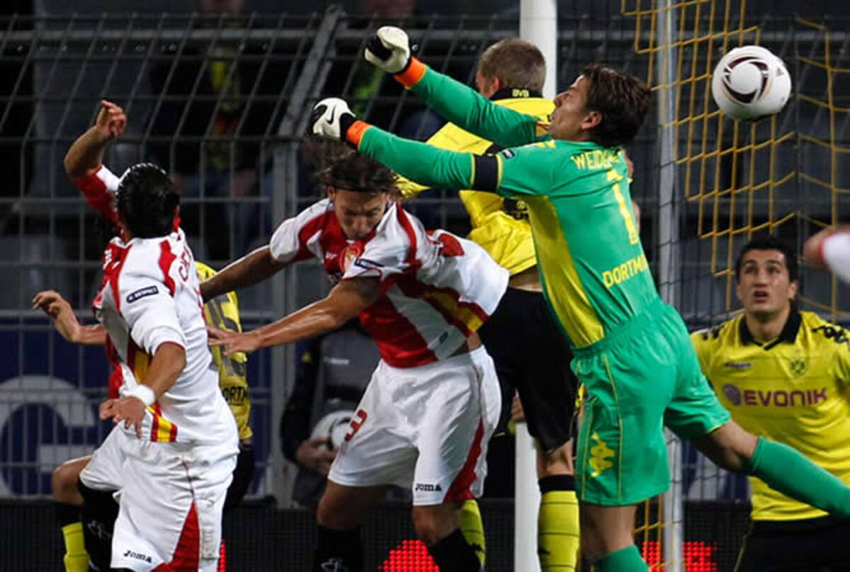 El portero del Borussia Dortmund Roman Weidenfeller intenta despejar ante la presencia del sevillista Alexis