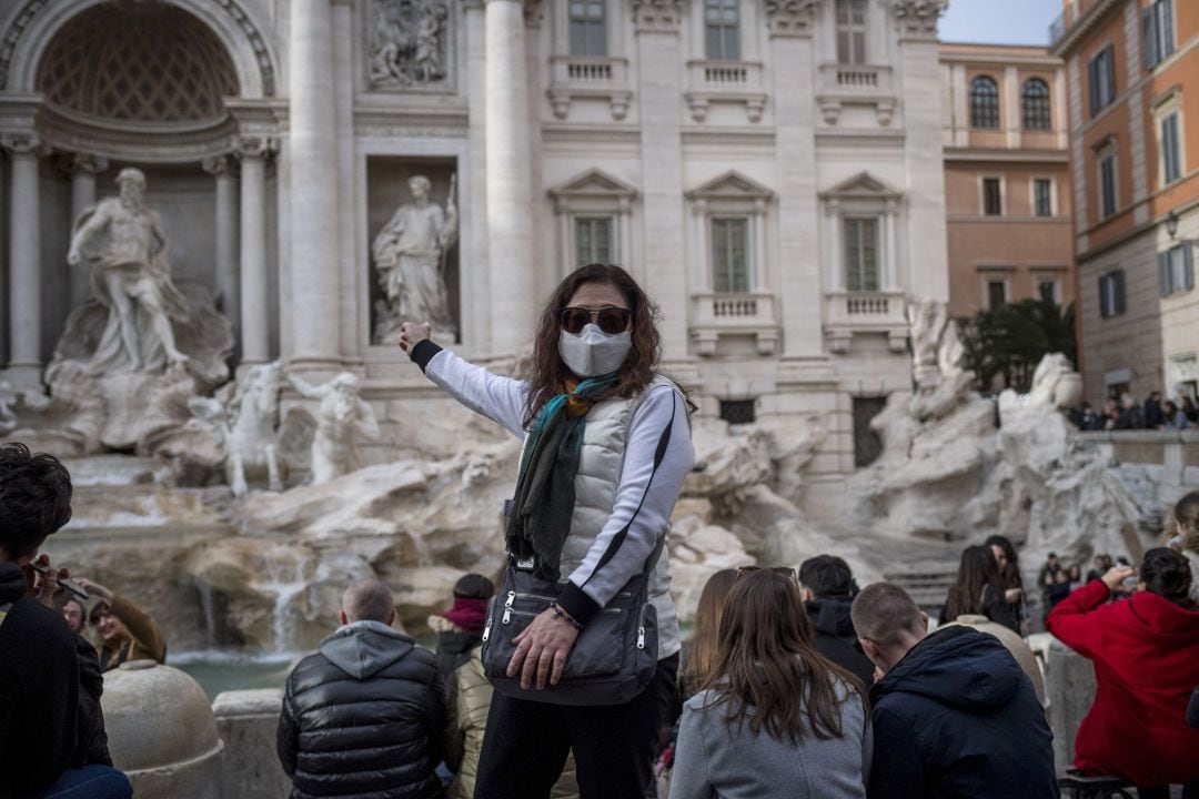 Turistas posan con mascarillas en la Fontana di Trevi, en Roma