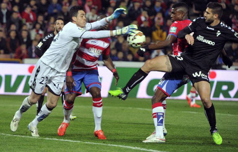 El guardameta del Eibar Jaimeintenta despejar un balón ante el delantero mexicano del Granada John Córdoba.