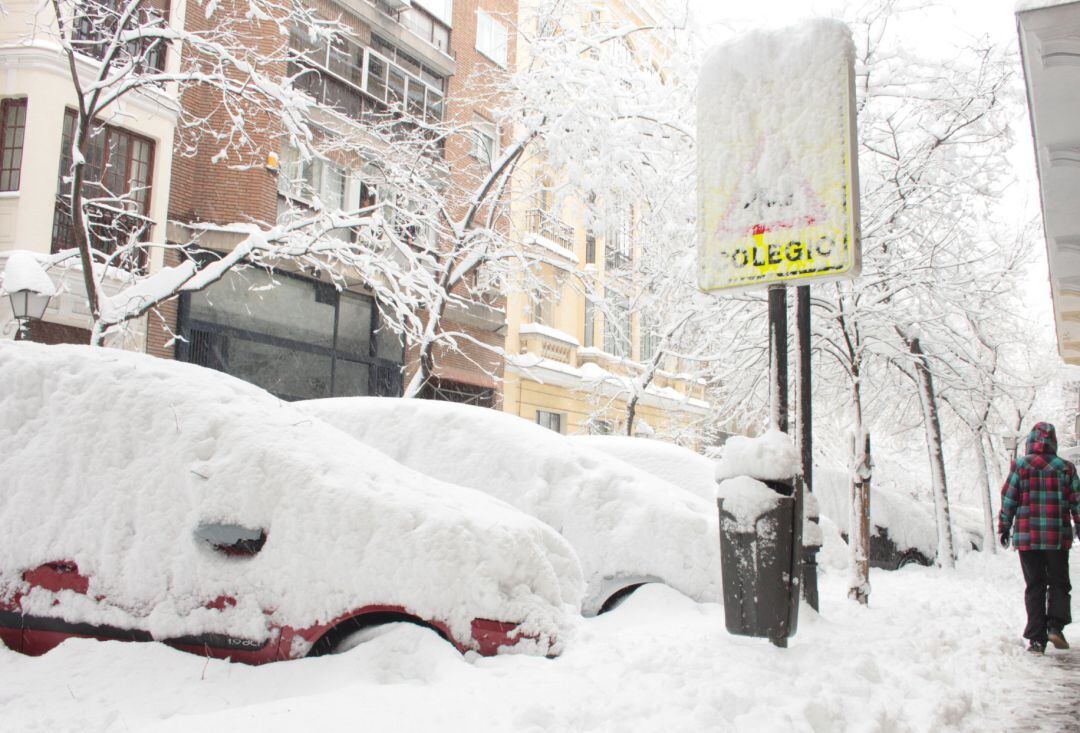 Una persona pasea por una céntrica calle cubierta de nieve junto al acceso de un colegio en Madrid (España) a 9 de enero de 2021.