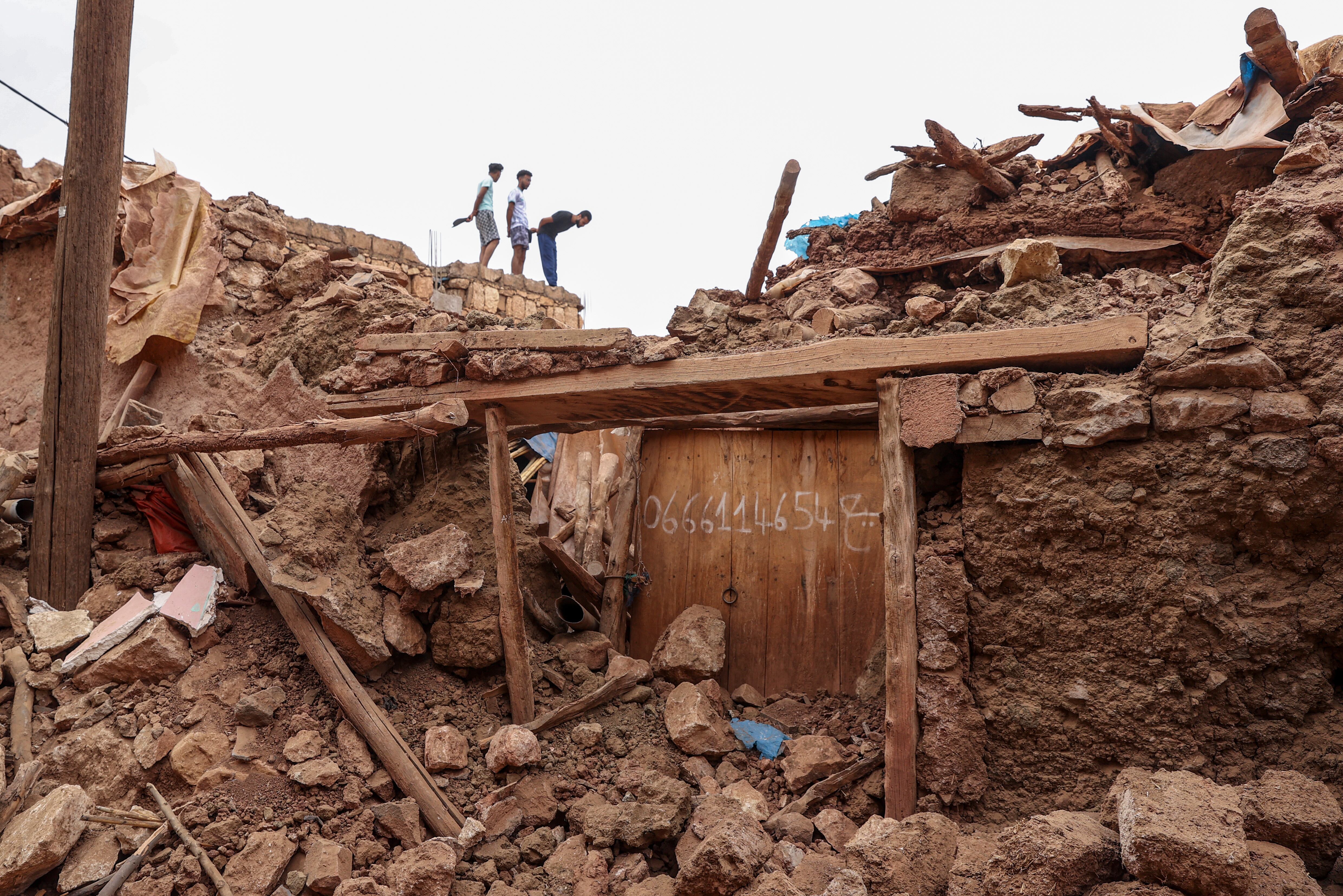 Varios jóvenes observan los edificios derruidos por el terremoto de Marruecos, en Asni, donde se ha instalado un albergue para afectados. EFE/ Kiko Huesca