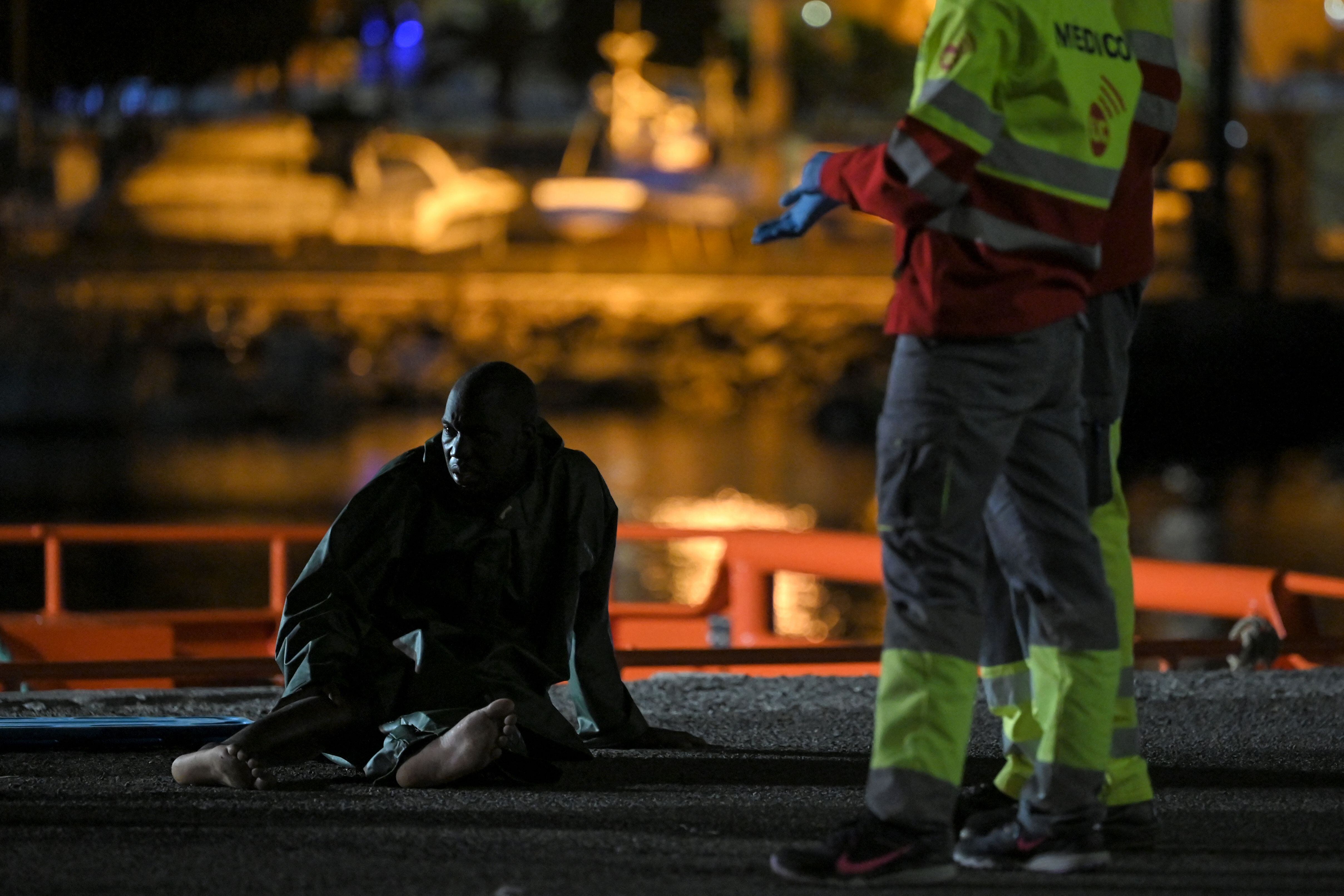 Personal de Emergencias junto a un migrante, en el puerto de Arguineguin (Islas Canarias) el 18 de noviembre de 2021