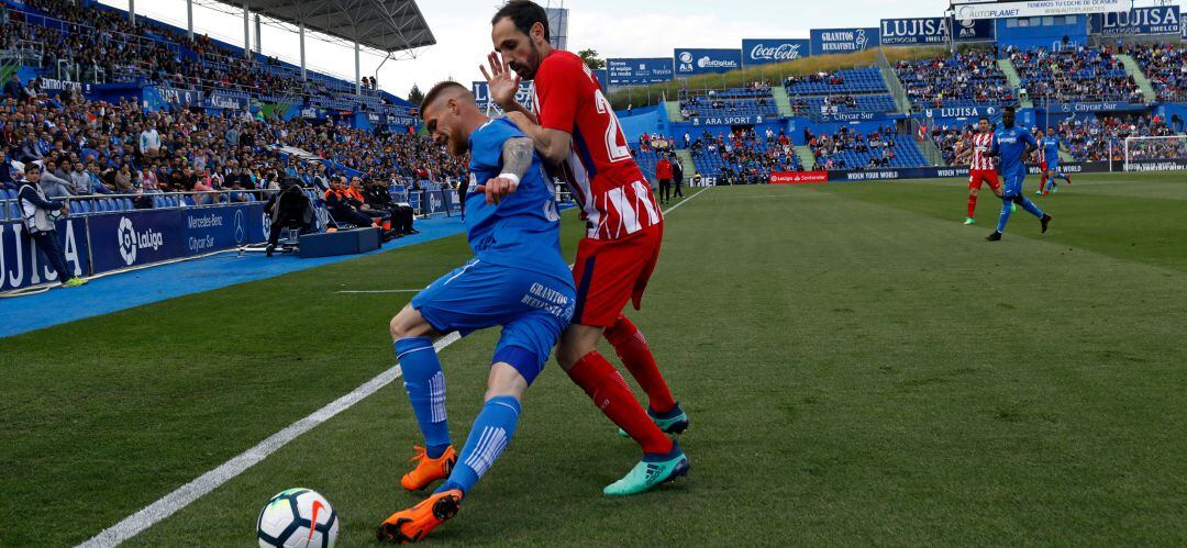 El azulón Antunes y el rojiblanco Juanfran pugnan por un balón en el último derbi entre Getafe y Atlético que terminó con triunfo visitante en el Coliseum.