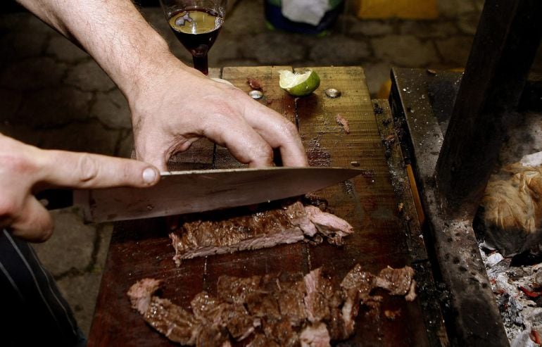 MED731. MEDELLÍN (COLOMBIA), 17/10/2015.- Fotografía del 16 de octubre de 2015 de un chef que corta carne durante un mano a mano de asados entre chefs de Argentina, Uruguay y Chile en el marco de Maridaje 2015 en Medellín (Colombia). Al aire libre, frente a cuatro parrillas y como si cocinaran en el jardín de su casa, chefs argentinos, uruguayos y chilenos mostraron en un festival gastronómico en Colombia parte de sus tradiciones a través del asado, la práctica culinaria más primitiva que existe. EFE/LUIS EDUARDO NORIEGA