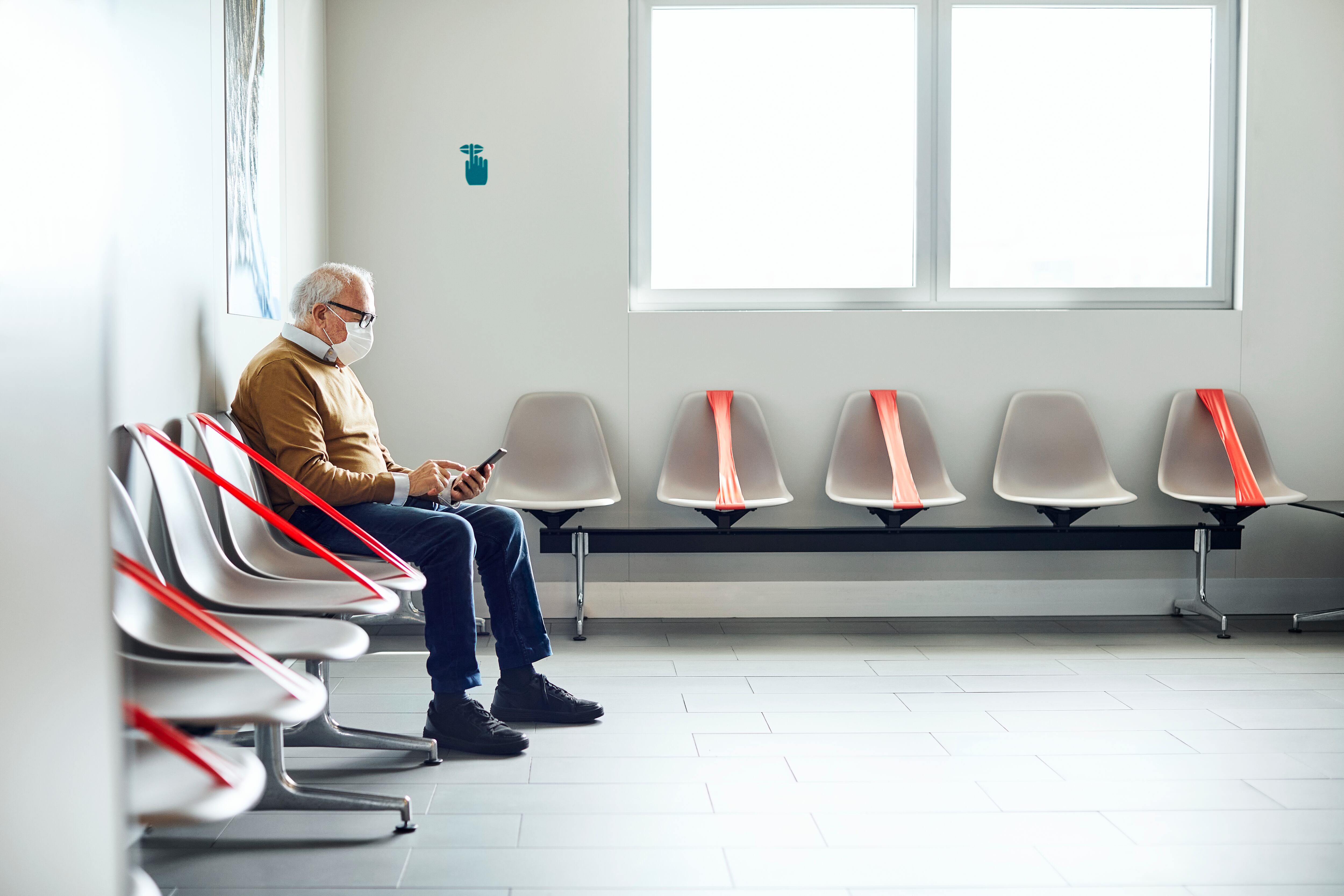 Un hombre de edad avanzada, con una mascarilla en la cara, aguarda en la sala de espera de un hospital