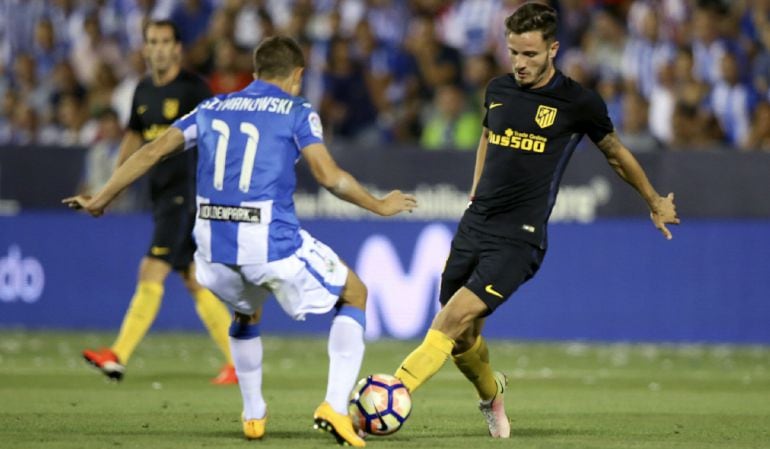 El centrocampista del At. de Madrid, Saúl (d), intenta llevarse el balón ante el jugador argentino del Leganés, Alexander Szymanowski, durante el encuentro correspondiente a la segunda jornada de primera división, disputado en el estadio de Butarque.