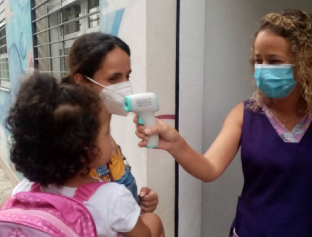 Una profesora toma la temperatura a una niña a la entrada de una escuela infantil