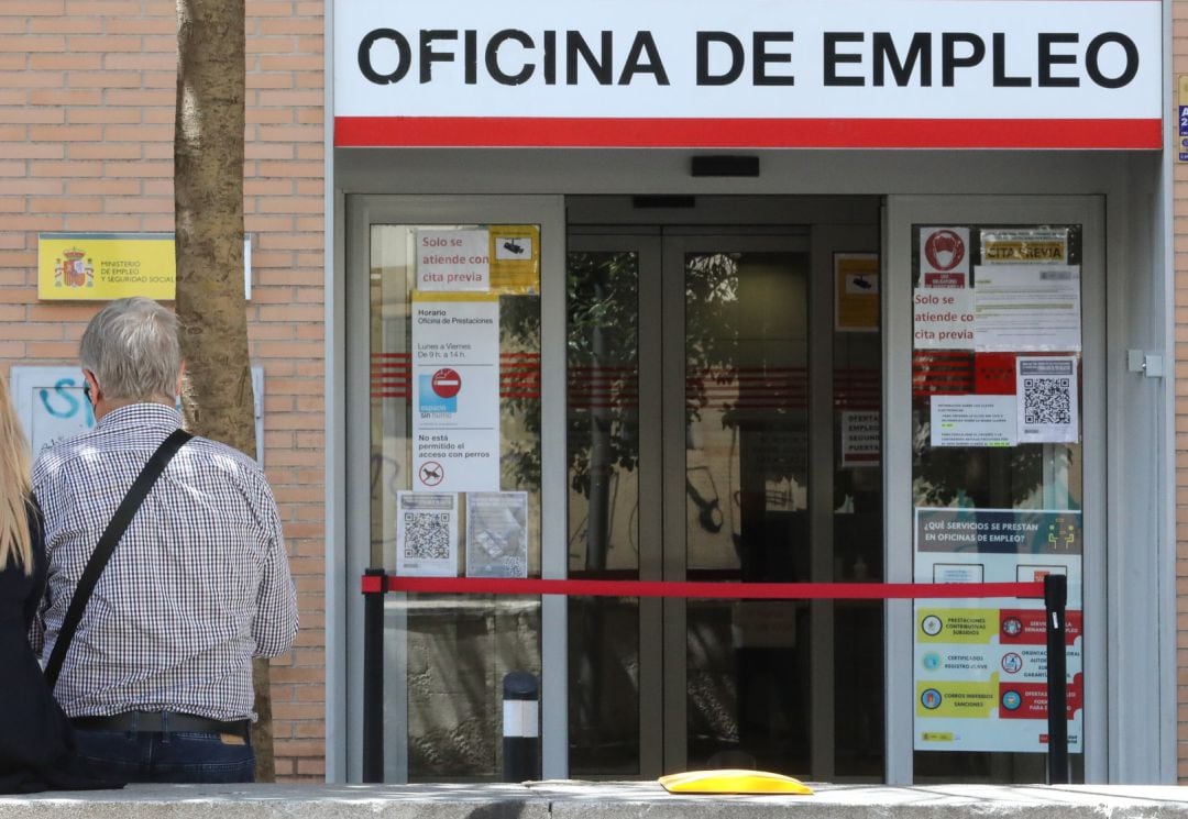 Dos personas sentadas frente a una oficina del SEPE.