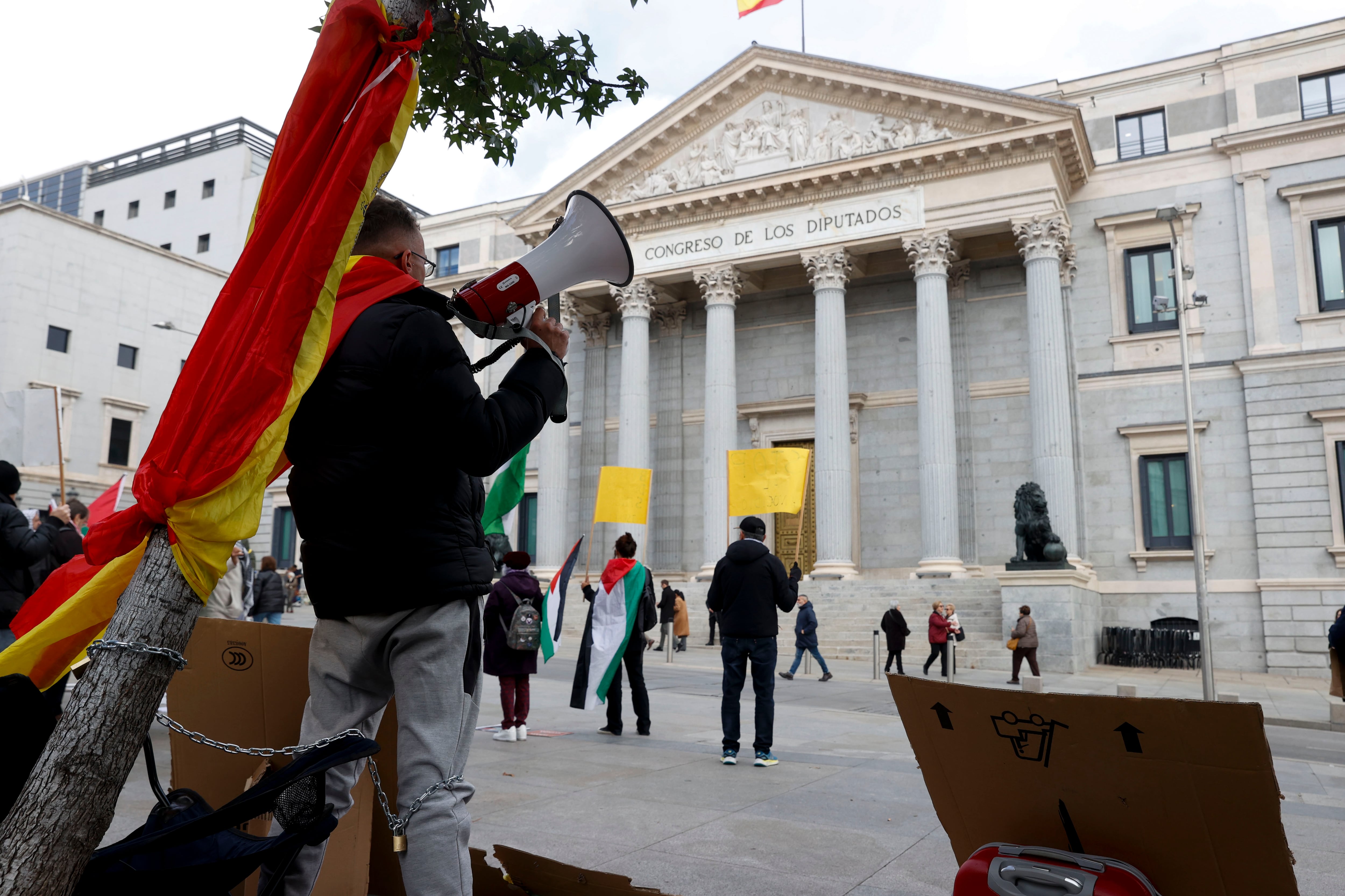 MADRID, 08/11/2023.- Un hombre de 28 años se ha encadenado a un árbol en la plaza de las Cortes, frente al Congreso, donde ha iniciado una huelga de hambre desde ayer en contra de la amnistía del procés porque asegura que contradice lo dicho por Pedro Sánchez en la campaña electoral. EFE/ Juan Carlos Hidalgo
