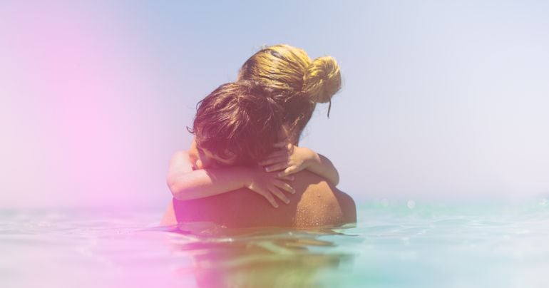 Un niño y su madre se abrazan en el mar. 