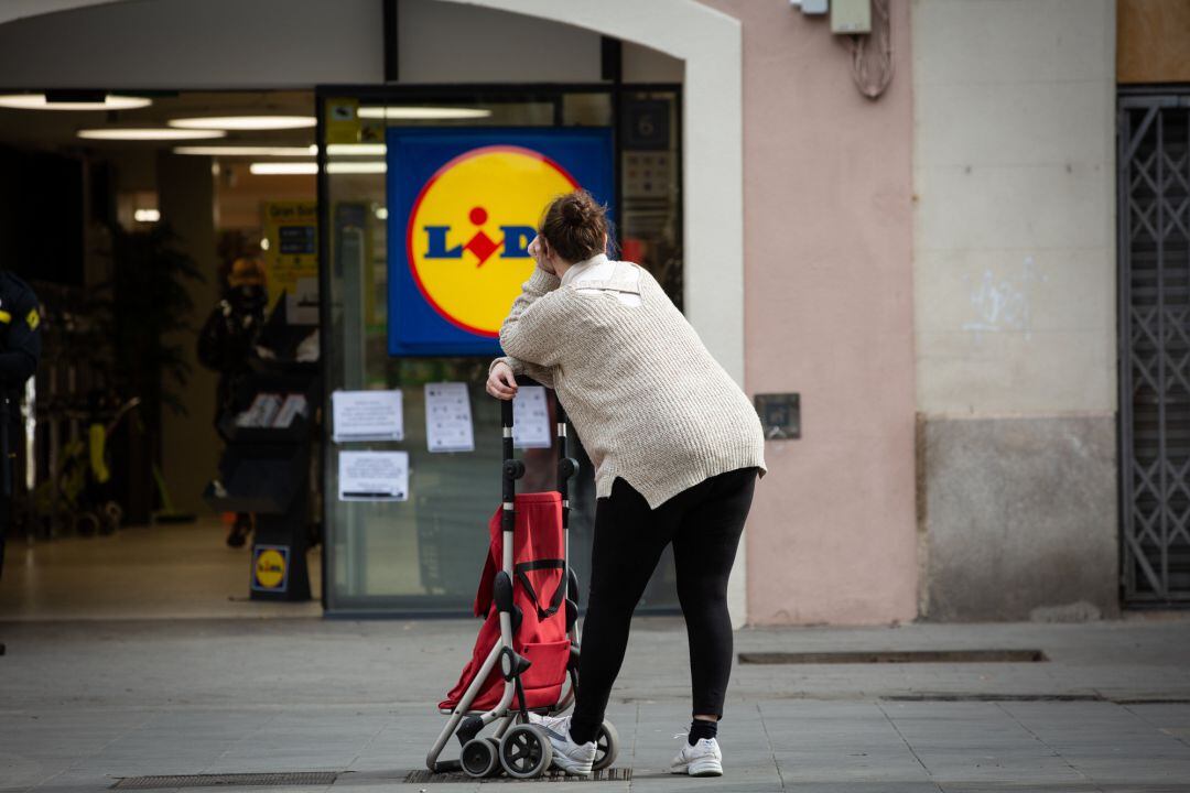 Una mujer espera con su carro de la compra a poder entrar a un supermercado Lidl, este martes.